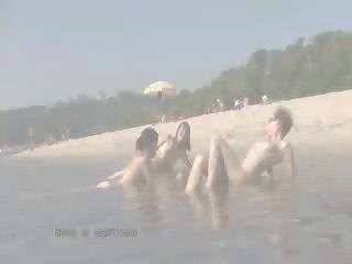 Un pubblico spiaggia heats su con due superiore bambola nudists